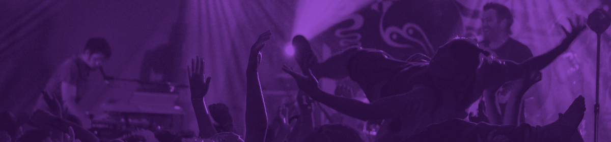 a band plays on stage while a concertgoer crowdsurfs in silhouette